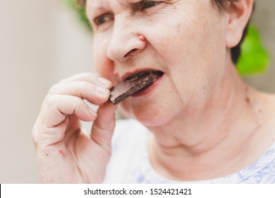 Senior Woman Eating Sweet Chocolate Outdoors - Portrait Of Cute Old Lady Enjoying Cocoa Snack - Concept Image For Healthy And Balanced Lifestyle