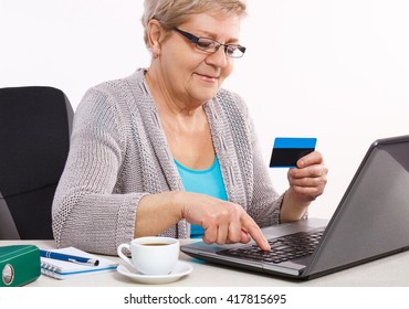 Senior Woman, An Elderly Pensioner With Credit Card And Laptop Paying Over Internet For Utility Bills Or Online Shopping, Surfing Internet, Typing On Computer Keyboard