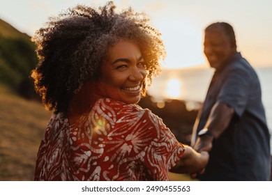 Senior woman embracing longevity and vitality while walking at sunset, holding her partner’s hand and smiling warmly. - Powered by Shutterstock