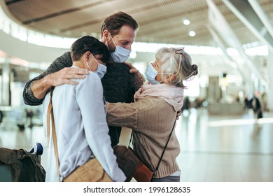 Senior woman embracing and welcoming family at airport terminal after arrival. Senior man hugging her son on arrival to airport post pandemic. - Powered by Shutterstock