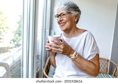 Senior woman enjoying afternoon at home. Happy senior woman day dreaming while looking through the window and enjoying in cup of coffee. Senior woman drinking coffee next to the window. - Powered by Shutterstock