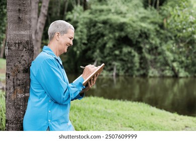 Senior Woman Enjoying Outdoor Sketching by a Tranquil Lake in a Lush Green Park - Powered by Shutterstock