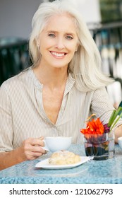 Senior Woman Enjoying Snack At Outdoor Cafe