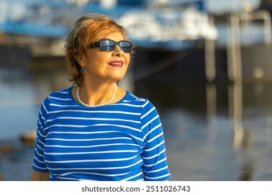 Senior woman enjoying a sunny day by the waterfront, dressed in - Powered by Shutterstock