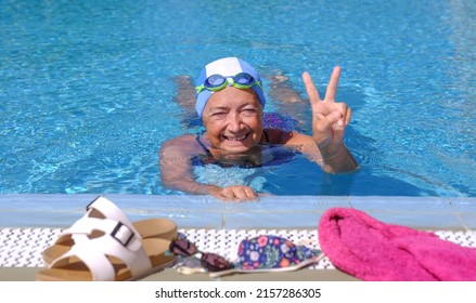 Senior Woman Enjoying Swimm Into The Outdoors Pool With Swimming Goggles And Cap - Active Elderly Female Enjoying Healthy Activity On A Sunny Day