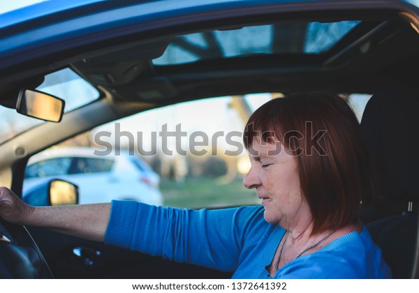 A senior woman enjoys a newly acquired car with\
modern systems of active and passive safety, navigation of voice\
commands. Panoramic roof.