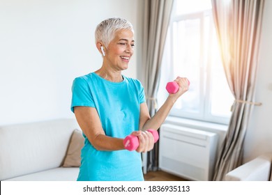 Senior woman exercise with dumbbells at home . happy mature woman doing arm workout using dumbbells. Elderly woman prefers healthy lifestyle - Powered by Shutterstock