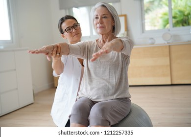 Senior woman exercising with her physiotherapist and swiss ball                               - Powered by Shutterstock