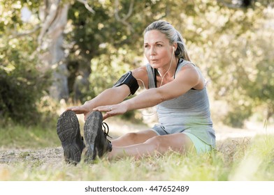 Senior woman exercising in park while listening to music. Senior woman doing her stretches outdoor. Athletic mature woman stretching after a good workout session. - Powered by Shutterstock