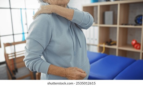 A senior woman experiences shoulder pain during a visit to a physiotherapy clinic, conveying a healthcare narrative. - Powered by Shutterstock