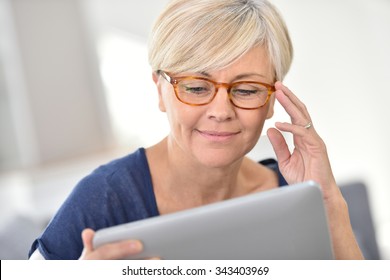 Senior Woman With Eyeglasses Browsing On Digital Tablet