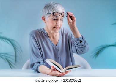 Senior Frau mit Brille hat Probleme mit Buchlesen. Indikation für Katarakte, Glaukom und Sehverlust bei älteren Patienten.