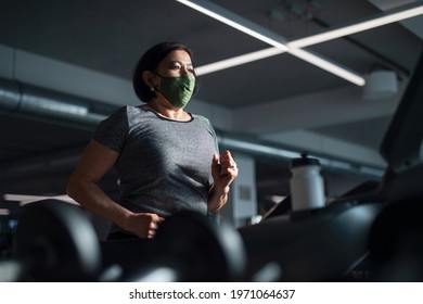 Senior Woman With Face Mask Doing Exercise On Treadmill In Gym, Coronavirus Concept.