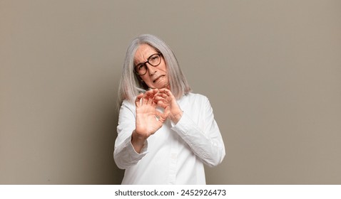 senior woman feeling disgusted and nauseous, backing away from something nasty, smelly or stinky, saying yuck - Powered by Shutterstock