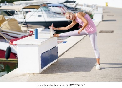 Senior Woman In Fitness Clothing Stretching Her Legs After Exercise.