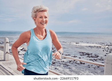 Senior woman, fitness and running at beach promenade, sky mockup and energy of health, wellness and workout. Elderly female, exercise and runner at ocean for happy sports, cardio training or marathon