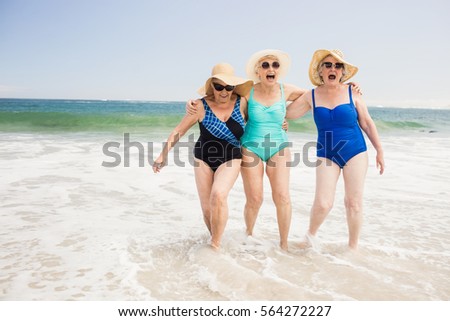 Senior woman friends playing in water at the beach
