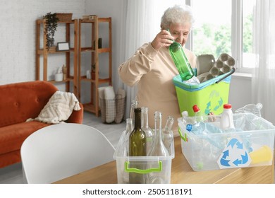 Senior woman with garbage bin sorting trash at home - Powered by Shutterstock