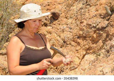 Senior Woman Geologist Tap A Rock Formation With A Hammer