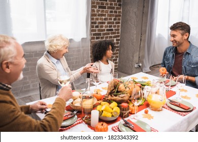 Senior Woman Gesturing While Talking To Multicultural Family During Thanksgiving Dinner