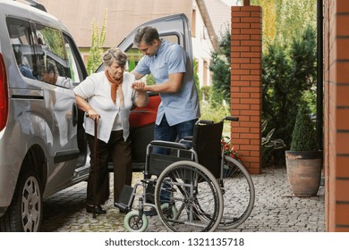 Senior Woman Getting Out Of The Car With The Help Of A Nurse