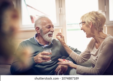 Senior Woman Giving Her Husband Medication Vitamins Supplement. 