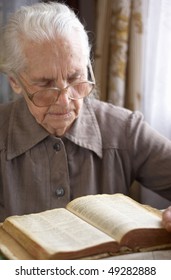 Senior Woman In Glasses Reading Old Bible