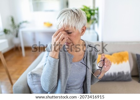 Senior woman in glasses rubs her eyes, suffering from tired eyes, ocular diseases concept Stok fotoğraf © 
