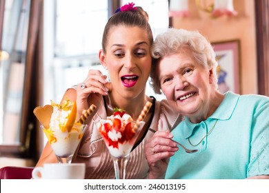 Senior Woman And Granddaughter Having Fun Eating Ice Cream Sundae In Cafe