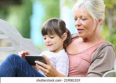 Senior Woman With Grandkid Playing Game On Smartphone