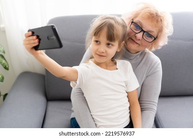 Senior Woman With Grandkid Playing Game On Smartphone