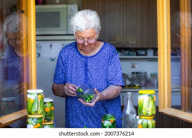 Senior Woman Or Grandmother Homemade Canning The Fresh, Bio Cucumbers To A Jars With Onion, Carrot And Dill, Food Concept