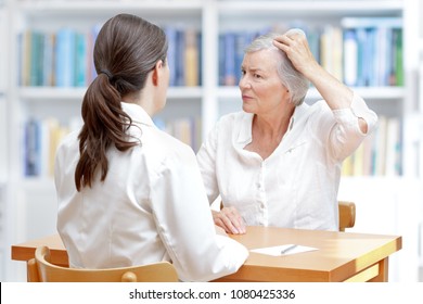 Senior Woman With Gray Hair Showing Her Thinning Hair Or Hair Loss To Her Female Doctor