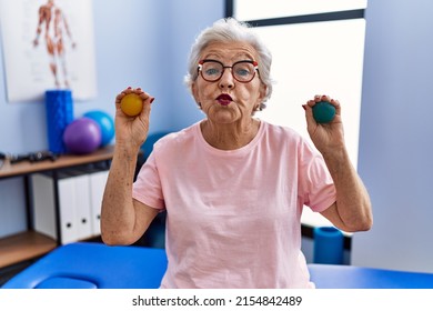 Senior woman with grey hair holding hands strength balls looking at the camera blowing a kiss being lovely and sexy. love expression. 