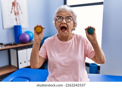 Senior woman with grey hair holding hands strength balls angry and mad screaming frustrated and furious, shouting with anger looking up.  - Powered by Shutterstock