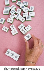 Senior Woman Hand Holding A Piece Of Mahjong Tile