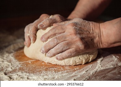 Senior woman hands knead dough on a table in her home kitchen