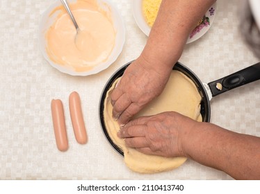 Senior Woman Hands Knead The Raw Dough On Black Pan With Oil For Homemade Pizza. Other Ingredients Are On The Table. Top View With Selective Focus. Process Of Cooking Pizza, Step 2