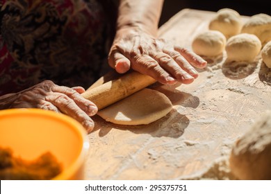 Senior woman hands rolling out dough in flour with rolling pin in her home kitchen - Powered by Shutterstock