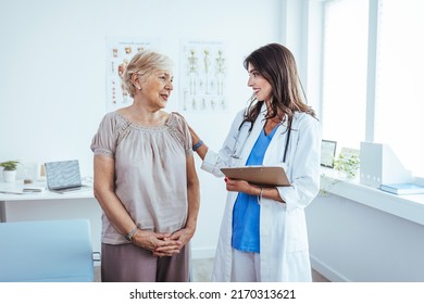 Senior woman having a consultation with her doctor. Senior woman having a doctors appointment. Doctor in blue uniform and protective face mask giving advice to Senior female patient at hospital - Powered by Shutterstock