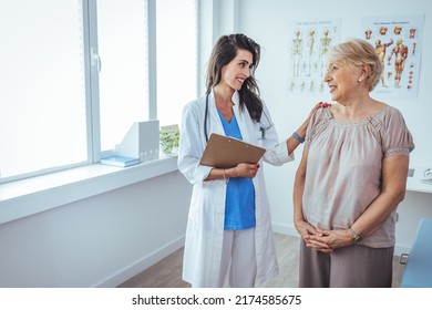 Senior Woman Having A Consultation With Her Doctor. Senior Woman Having A Doctors Appointment. Doctor In Blue Uniform And Protective Face Mask Giving Advice To Senior Female Patient At Hospital