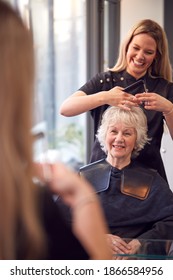 Senior Woman Having Hair Cut By Female Stylist In Hairdressing Salon