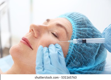 Senior woman having hyaluronic acid injection at beauty salon