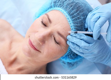 Senior woman having hyaluronic acid injection at beauty salon