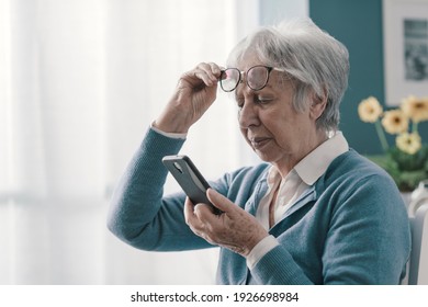 Senior woman having vision problems, she can't read the messages on her smartphone