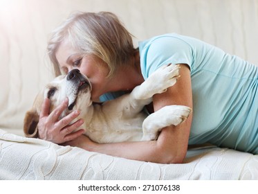 Senior woman with her dog on a couch inside of her house.