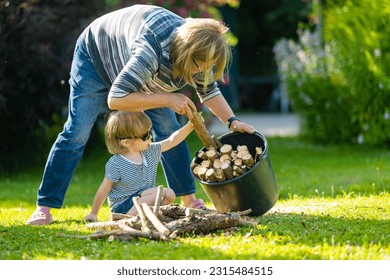 Senior woman and her grandson gathering dry firewood logs. Dry chopped firewood logs stacked up on top of each other in a pile. - Powered by Shutterstock