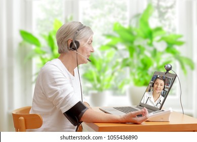 Senior Frau in ihrem Wohnzimmer vor einem Laptop, der während eines Videoanrufs mit ihrem Arzt für Kardiologie ihren Blutdruck überprüft