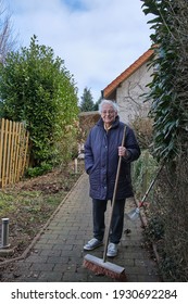 Senior Woman Holding A Broom After Cleaning A Path Way. Seasonal Spring Garden Work.