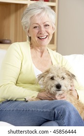 Senior Woman Holding Dog On Sofa